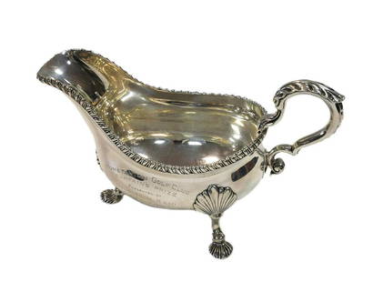 An early George III 18th century silver sauce boat, mark of William Grundy, London 1765, of: An early George III 18th century silver sauce boat, mark of William Grundy, London 1765, of traditional form with gadrooned rim and leaf capped scroll handle, presentation engraving to the side, raise