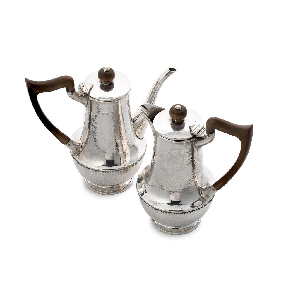 A George V silver ‘Arts & Crafts’ style bachelor’s coffee pot and hot water jug,: A George V silver ‘Arts & Crafts’ style bachelor’s coffee pot and hot water jug, mark of A.E. Jones, Birmingham 1922, both of tapering cylindrical form with hammered finish, bulbous