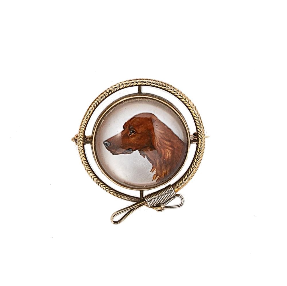 A reverse painted crystal intaglio brooch, depicting a red setter dog, with a lead style border,: A reverse painted crystal intaglio brooch, depicting a red setter dog, with a lead style border, diameter 3cm, pin and revolver fitting, unmarked, tested as 9ct gold, weight 11.2g