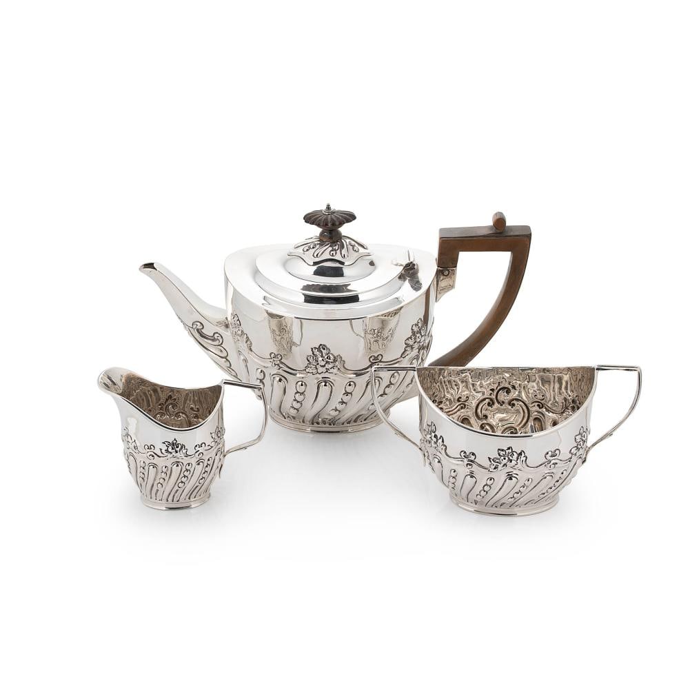 A Victorian silver three-piece tea set, mark of Charles Stuart Harris, London 1899, the teapot of: A Victorian silver three-piece tea set, mark of Charles Stuart Harris, London 1899, the teapot of oval form, lower with repouss? foliate and scroll decoration around an abstract scroll edged vacant ca