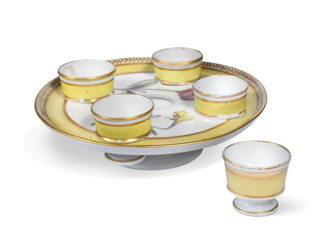 A Coalport egg cup stand for five egg cups, circa 1805,: A Coalport egg cup stand for five egg cups, circa 1805, the stand painted with named botanical specimens Rose Cockle and Least Daffodil, with a yellow ground and gilt floral border 19.5cm diameter