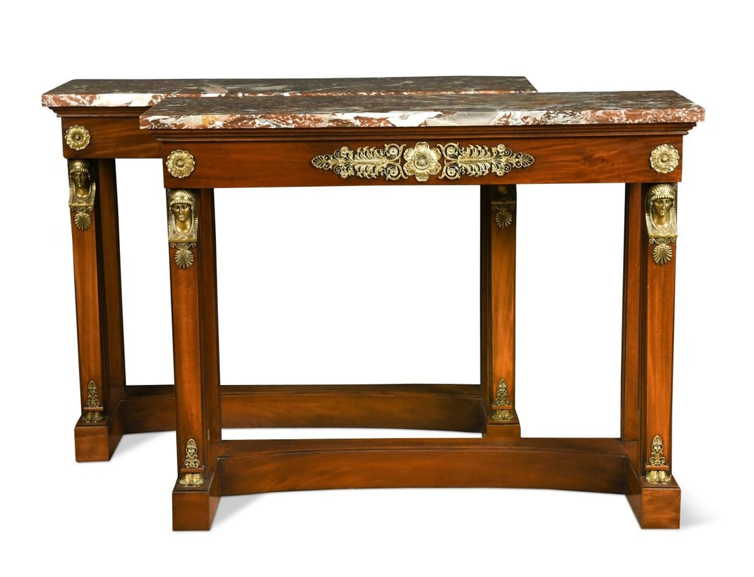 A pair of Empire style mahogany console tables, 19th century,: A pair of Empire style mahogany console tables, 19th century, decorated with gilt metal mounts, the marble tops raised on square tapered supports headed by female busts on shaped plinth bases 95.5 x 1