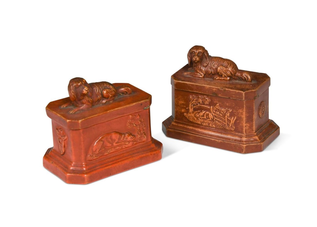 Two Bodenbach redware lidded boxes, 19th century,: Two Bodenbach redware lidded boxes, 19th century, each modelled as oblong plinths with canted sides relief decorated with hunting scenes and rosettes, the lids moulded with spaniel finials, one marked