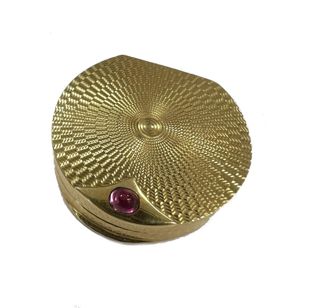 A mid 20th century 18ct gold pill box, retailed by Asprey,: A mid 20th century 18ct gold pill box, retailed by Asprey, mark of Ramsden & Roed, London 1967, of D shaped form, decorated all over with engine turned engraving, piano hinged cover with cabochon ruby