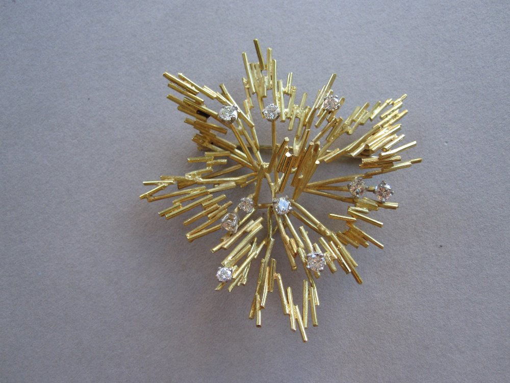 An 18ct gold and diamond brooch probably by Andrew Grim: An 18ct gold and diamond brooch probably by Andrew Grima, the asymmetrical open starburst of fine short gold rods scattered with ten round brilliant cut diamonds, hallmarked London 1963, sponsor's mar
