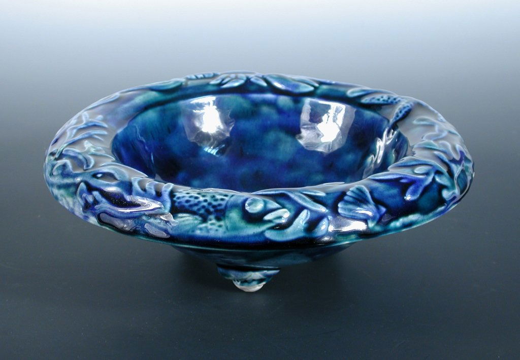 Kate Malone, a stoneware bowl,: Kate Malone, a stoneware bowl, the rim with raised images of sea creatures beneath a splashed blue and green glaze, the three feet modelled as shells, unmarked 9 x 26cm (4 x 10in)