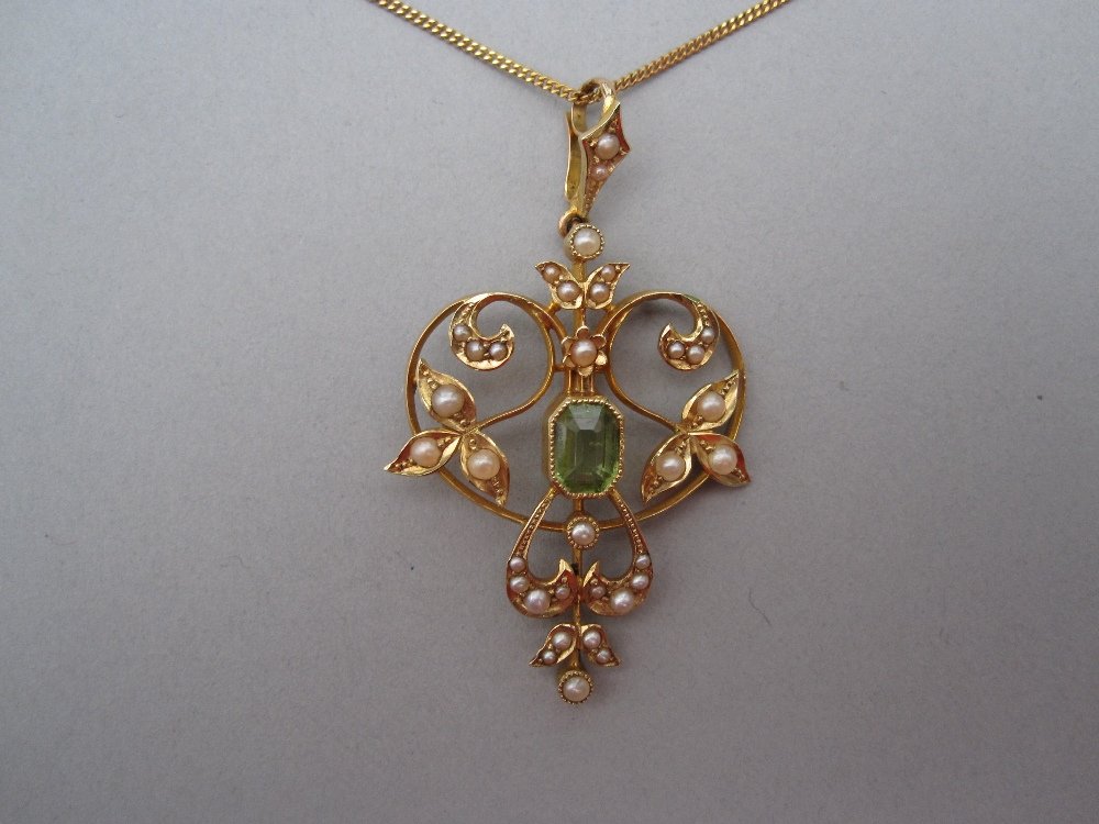 An Edwardian art nouveau peridot and seed pearl: An Edwardian art nouveau peridot and seed pearl pendant, millegrain set to the centre with an octagonal step cut peridot, in an open double heart of twining leaves and stems set with graduated seed pe