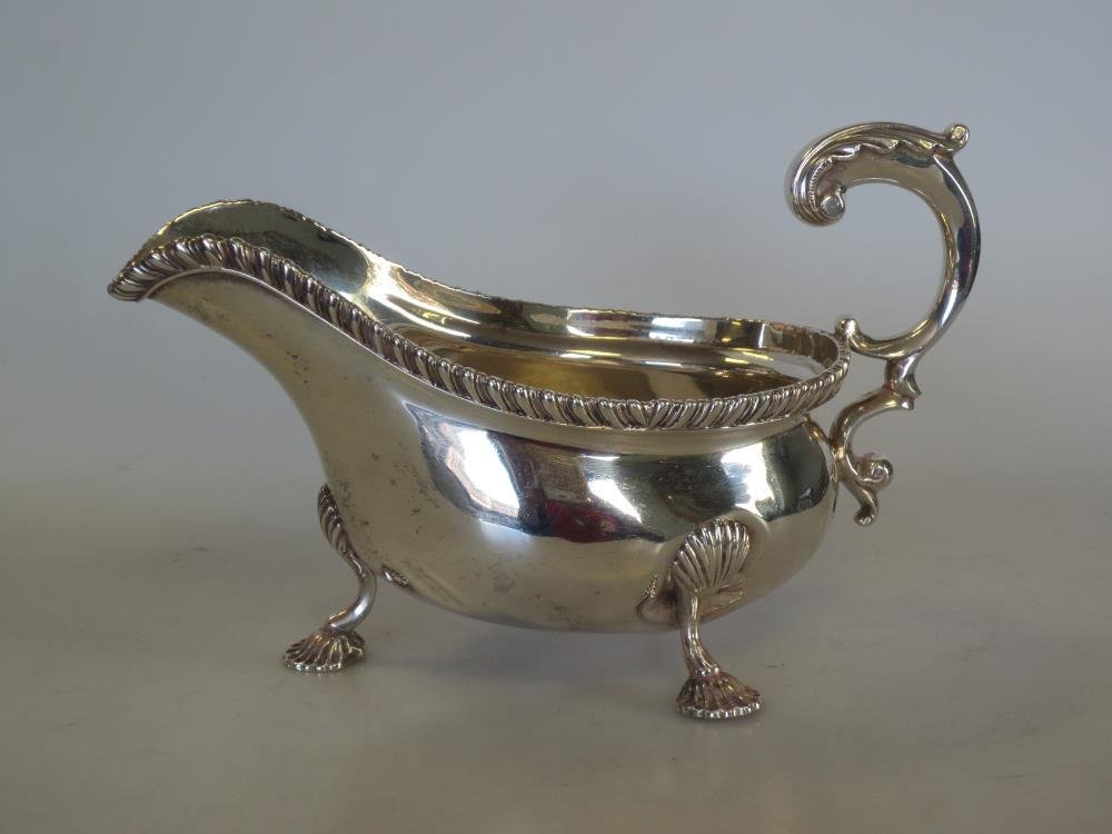 An Edwardian silver sauce boat,: An Edwardian silver sauce boat, by Charles Stuart Harris, London 1909, oval with gadrooned edge, leaf capped flying scroll handle and raised on three shell headed shell feet, 11.5cm, 10.12oz
