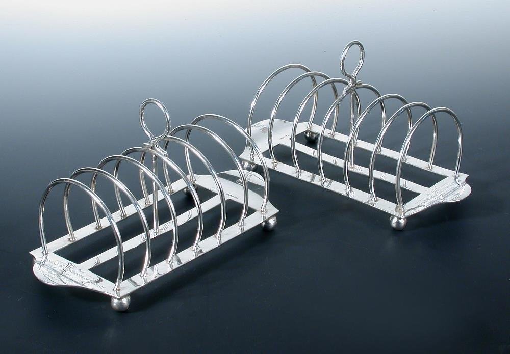 A pair of silver seven bar toast racks,: A pair of silver seven bar toast racks, by the Atkin Bros, Sheffield 1936, and with Dublin import marks for the same year, each on a plain flat rectangular base with turned up handle to each end, the