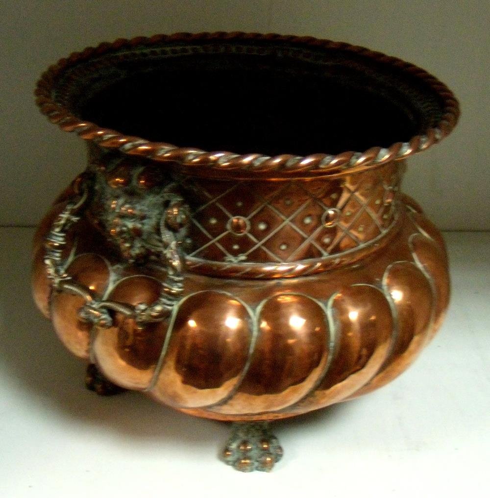 A mid 18th century copper wine cooler,: A mid 18th century copper wine cooler, the rope twist circular rim above lion mask and foliate cast handles to the cylindrical neck worked with diamond diaper above lobes to the bun shaped body on fou