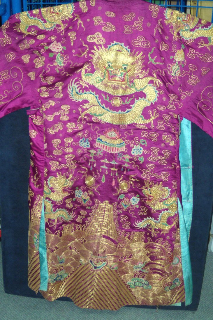 A late 19th/early 20th century plum silk three quarter: A late 19th/early 20th century plum silk three quarter length jacket embroidered with four clawed dragons chasing gold thread pearls amongst clouds and bats, the collar and opening with silver thread 