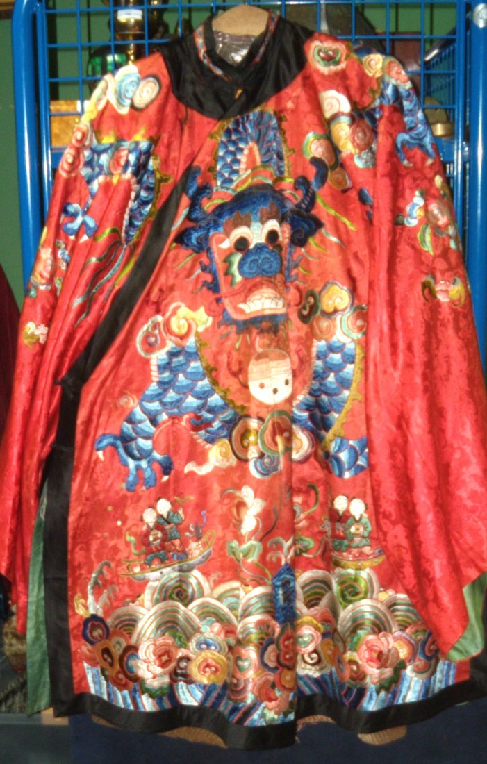 A late 19th /early 20th century red silk three quarter: A late 19th /early 20th century red silk three quarter length robe embroidered with four clawed dragons above pairs of children in boats flanking lotus on the front and pairs of fish flanking exotic b