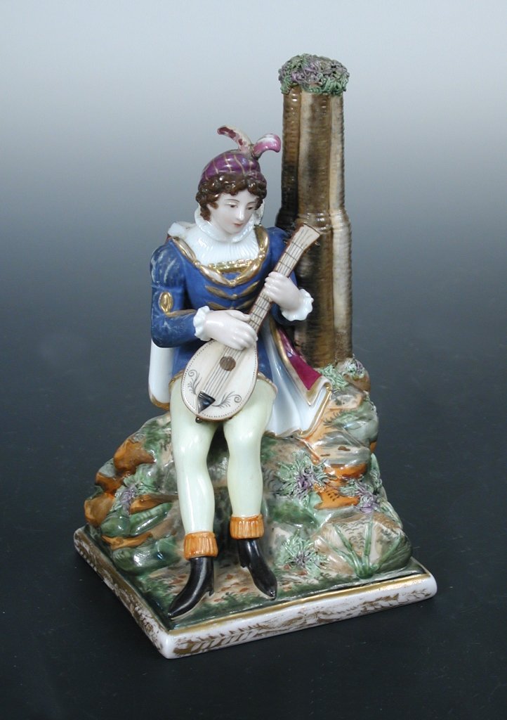 A mid 19th century Popov porcelain figure of a: A mid 19th century Popov porcelain figure of a Renaissance lutanist, seated by a cluster column on grassy knoll, the edge of the square base gilt, monogram in underglaze blue, 17cm (6.75 in) high (R)