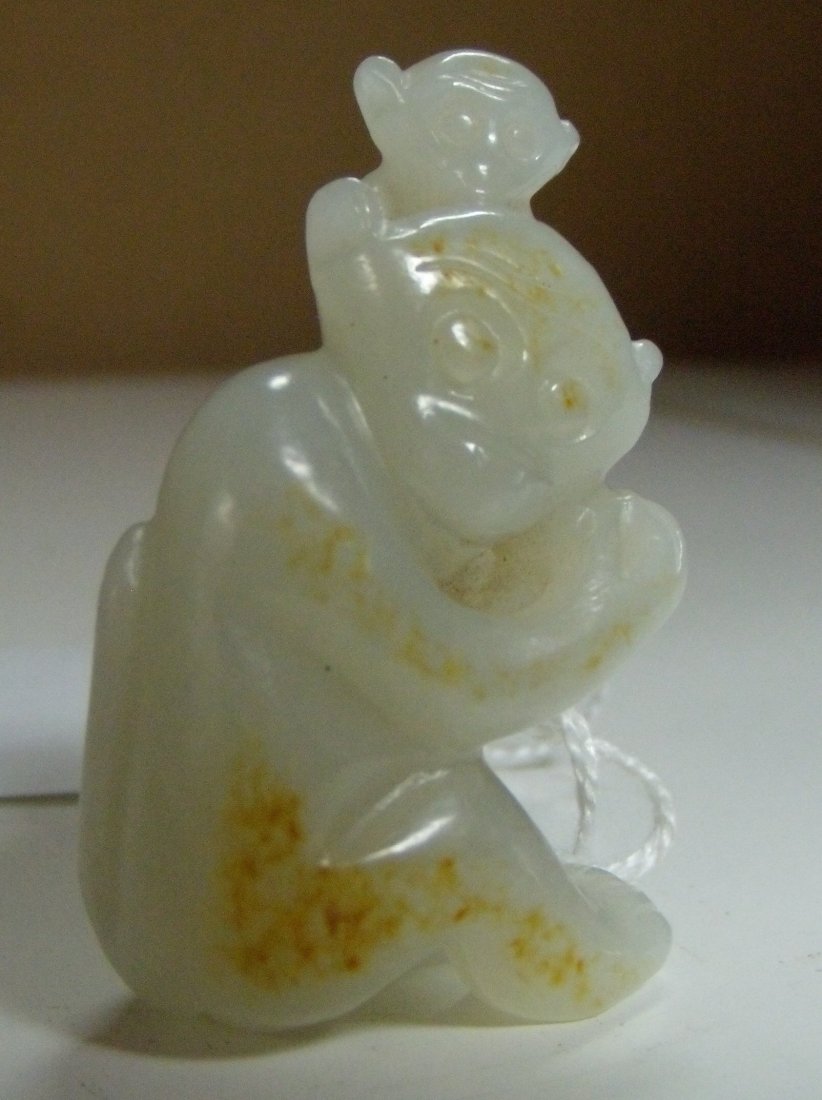 A two tone nephrite jade monkey and baby pendant,: A two tone nephrite jade monkey and baby pendant, the pale grey stone with the toffee brown crust used to define the arm, leg and forehead of the parent monkey seated with her baby on her shoulder, 4.