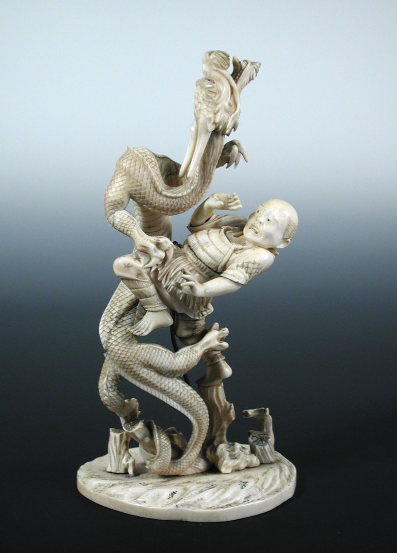 A late 19th/early 20th century ivory sectional group: A late 19th/early 20th century ivory sectional group of a dragon entwined with a man as they both rise up from cut tree trunks, the oval base carved as swirling water, trace of a signature, 22cm (8.75