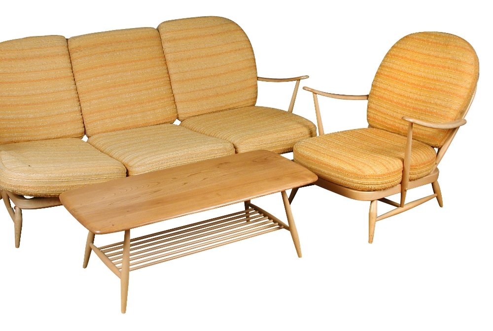 An Ercol stick back three piece suite,: An Ercol stick back three piece suite, comprising sofa and two armchairs, with original mustard and orange upholstered cushions, together with an Ercol coffee table (4)