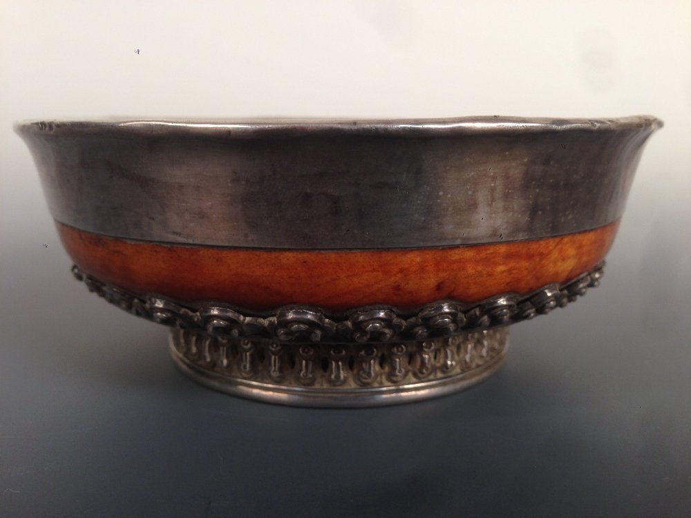 A Tibetan silver mounted wooden bowl, probably 19th: A Tibetan silver mounted wooden bowl, probably 19th century, the interior with a plain lining, the exterior of the foot with pierced and chased bands enclosing a cruciform rosette within the foot rim,