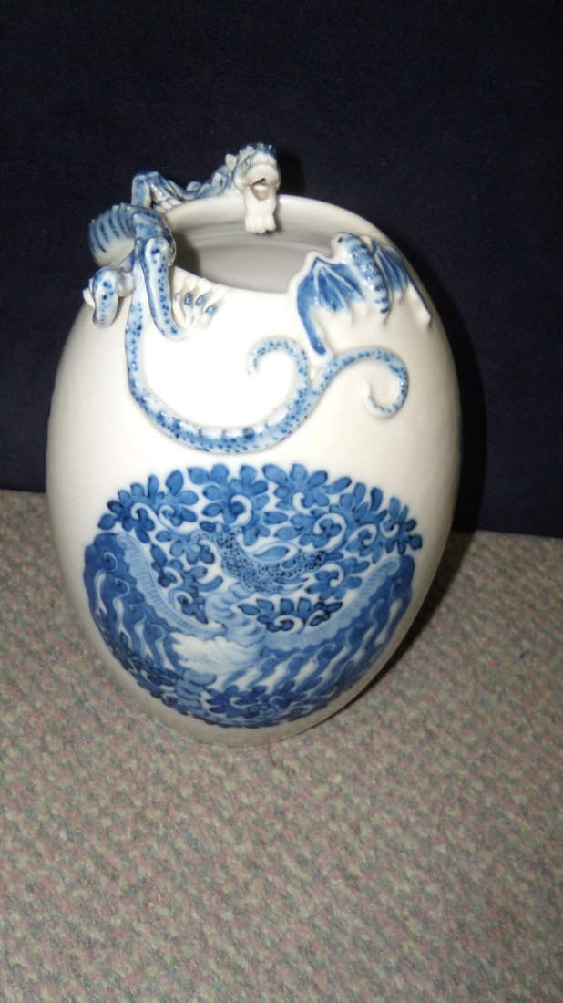 A Qianlong style blue and white vase,: A Qianlong style blue and white vase, the rim of the ovoid body applied with a dragon facing a bat above three roundels painted with winged beasts among foliage, seal mark of Qianlong, 18.5cm (7.25 in