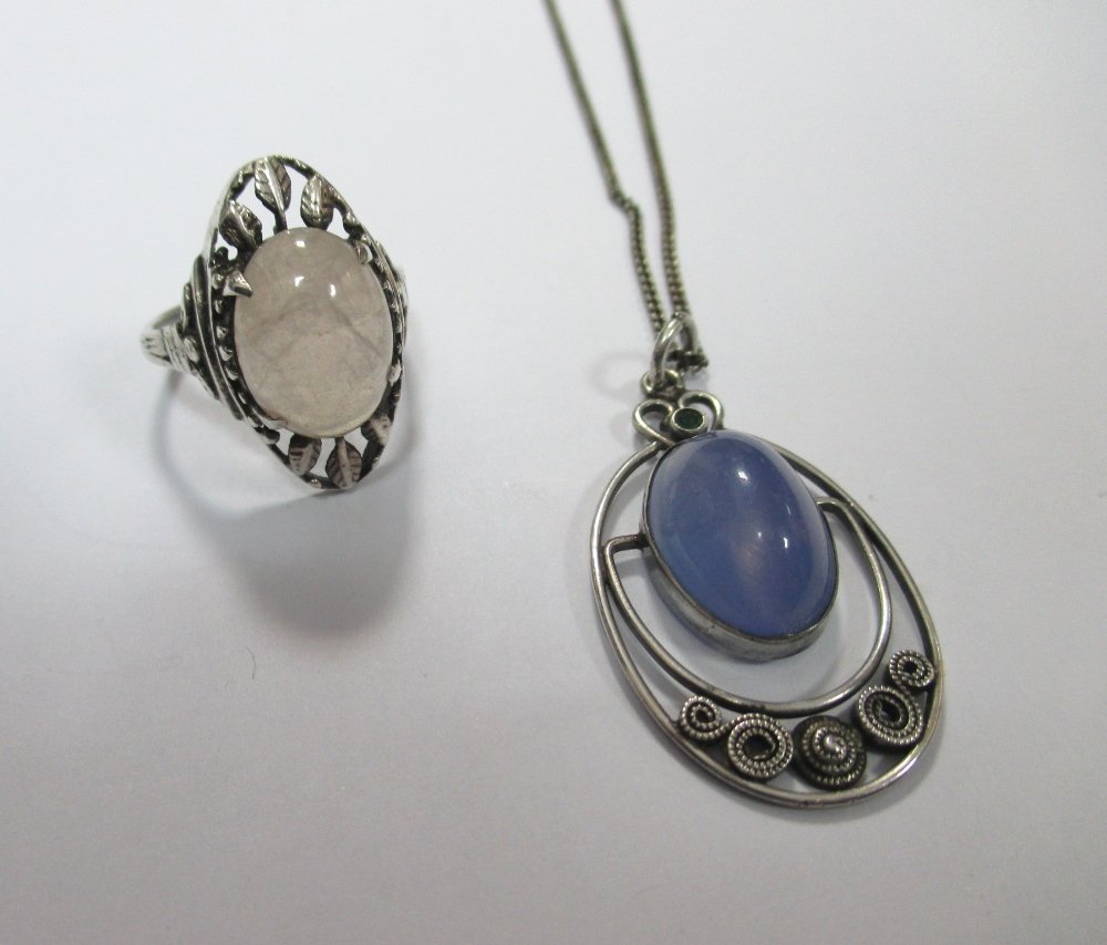 An Arts and Crafts style ring in the manner of Bernard: An Arts and Crafts style ring in the manner of Bernard Instone and an Arts and Crafts style pendant, the ring set with an oval rose quartz cabochon set in four claws to an openwork oval with three whi
