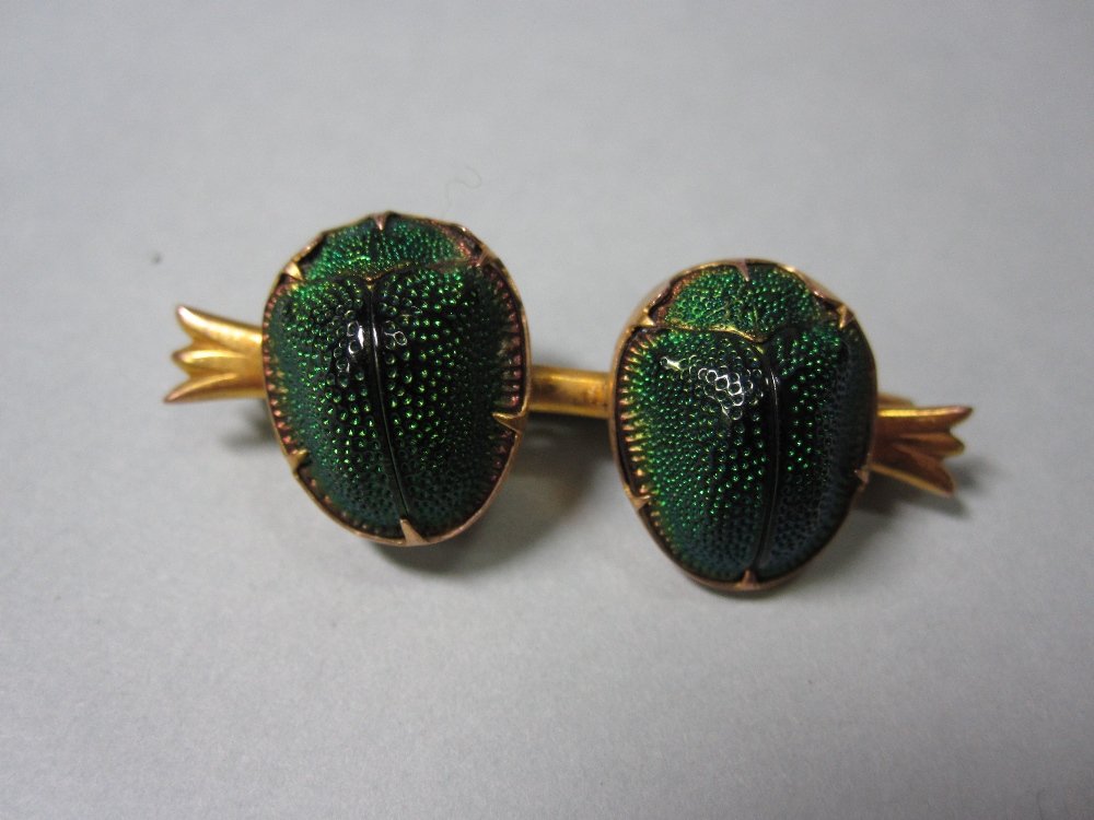 A Victorian double scarab beetle bar brooch,: A Victorian double scarab beetle bar brooch, the two irridescent green carapaces collet set side by side on a short bar with flared trifurcated terminations, length 3.7cm