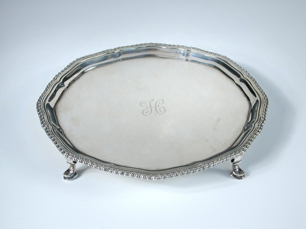 A small silver salver,: A small silver salver, by Searle and Co, London 1927, circular with gadrooned edge, raised on four hoof feet, initialled, 20.75cm, 13.87oz