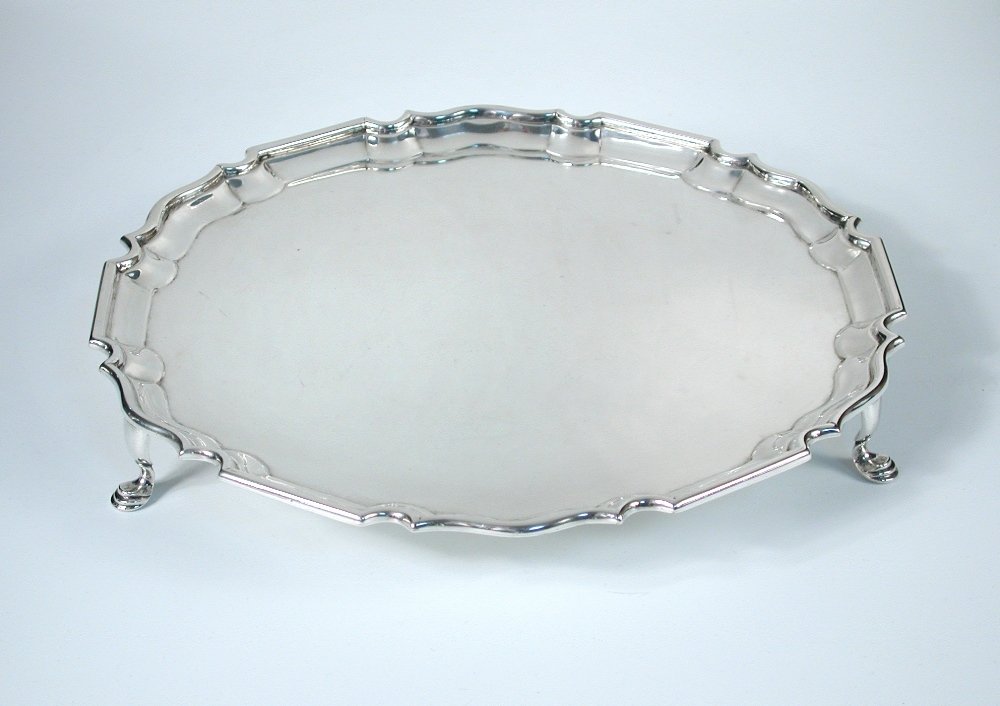A Victorian silver salver: A Victorian silver salver by Charles Stuart Harris, London 1897, circular with shaped moulded edge, raised on three hoof feet, 25.5cm, 16.8oz