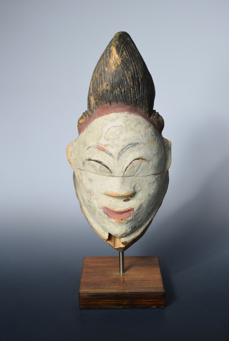 An early 20th century Punu Gabon wooden mask for a: An early 20th century Punu Gabon wooden mask for a stilt dance, modelled as the head of a dead girl, the white face with red mouth and line below her black hair, 31cm (12.25 in) high Sold on behalf of