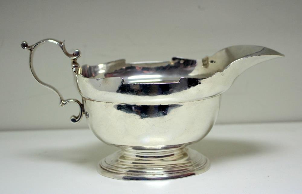 A large silver sauceboat,: A large silver sauceboat, by Richard Comyns, London 1930 of very heavy gauge, oval with shaped edges, double scroll handle and raised on a stepped oval foot, 10.25cm high, 12.7oz