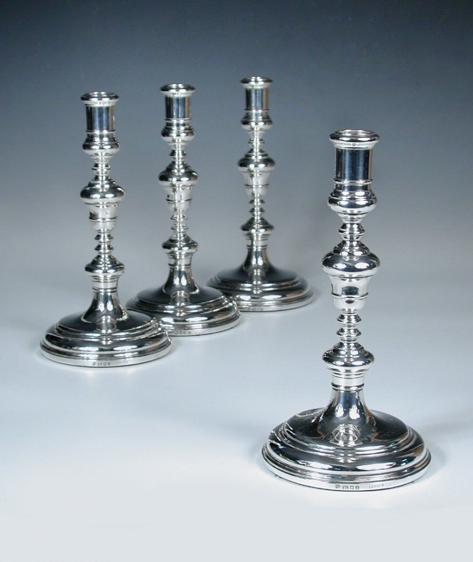 A set of four silver table candlesticks,: A set of four silver table candlesticks, by Richard Comyns, London 1936, each raised from a plain circular foot below a baluster stem supporting a spool socket, uninscribed, 23.5cm, loaded (4)