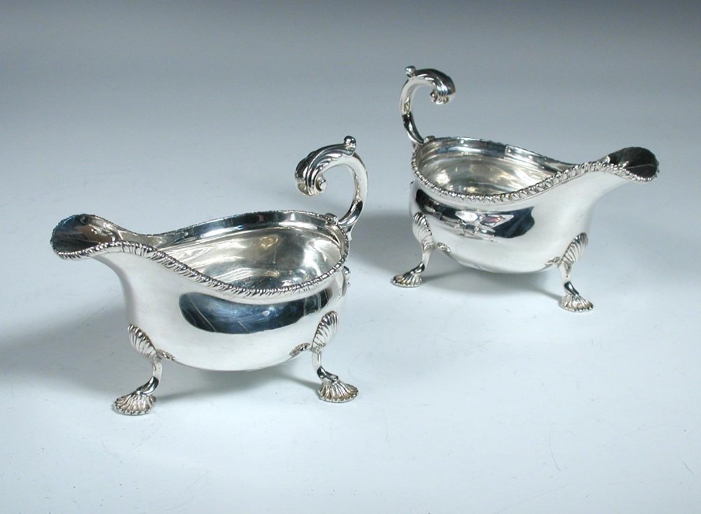 A pair of Edwardian silver sauceboats,: A pair of Edwardian silver sauceboats, by Charles Stuart Harris, London 1902, each of oval shape with gadrooned edge, leaf capped scrolled handle and raised on three shell headed shell feet, 1920's pr
