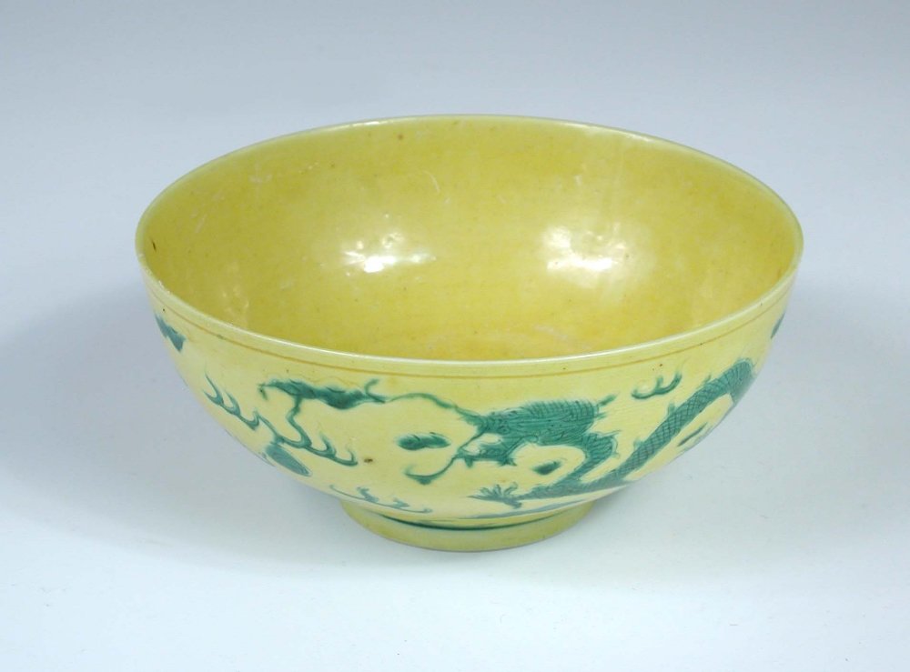 A yellow ground bowl, six character mark and probably: A yellow ground bowl, six character mark and probably period of Tongzhi, the rounded exterior incised with two green dragons chasing flaming pearls amongst clouds, 12.5cm (5 in) diameter