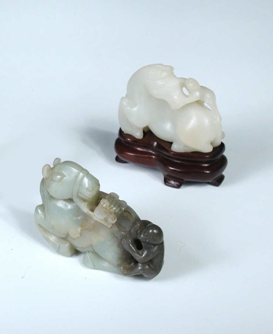 A green and grey jade group: A green and grey jade group of a bridled reclining horse looking back to a fly on its back between the reins held by the grey monkey at its tail, 5.5cm (2.25 in) wide
