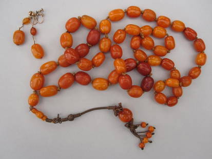 A vintage butterscotch amber tassel necklace and pair: A vintage butterscotch amber tassel necklace and pair of matched earrings, the long rope of graduated oval amber beads of varying colour in a knotted string without clasp, meeting at the centre to sus