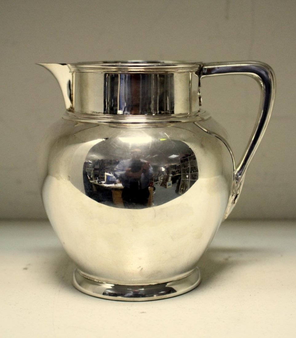 A silver milk jug,: A silver milk jug, by Charles Stuart Harris & Sons, London 1912, of plain baluster form with sparrow beak spout, moulded bands to the collar and handle, crested, 12cm high, 12.13oz