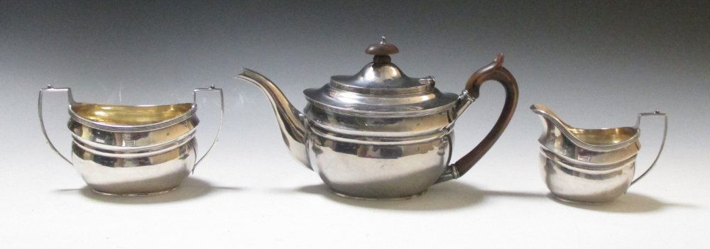A silver three piece tea set,: A silver three piece tea set, by Charles Stuart Harris, London 1927, comprising:- a teapot of compressed oval form with moulded girdle and reeded edge below a hinged cover, 15.5cm high, together with