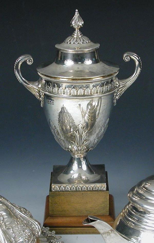 AN EDWARDIAN SILVER CUP AND COVER: An Edwardian silver two handled Cup and Cover, by Charles Stuart Harris, London 1904, of vase shape, the lower body embossed with stiff leaf decoration over a square foot, the cover with wrythen finia