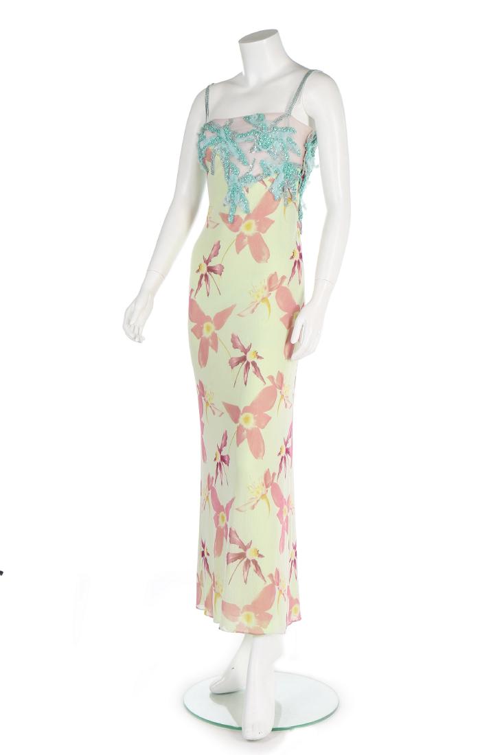 A Versace printed tulle evening gown, Spring-Summer: Description: A Versace printed tulle evening gown, Spring-Summer 1999, labelled and size 38, the primrose ground printed with scattered pink flowerheads, the nude illusion bodice with turquoise Oroton