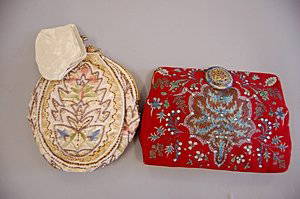 Two evening bags, 1930s, the first of red silk paint: Two evening bags, 1930s, the first of red silk painted with leaf forms and studded with pastes, enamelled and beaded clasp, 21cm, 8 1/4in; the other of ivory satin embroidered with palmettes, bugle