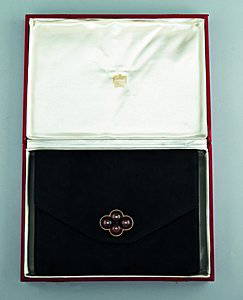 A Cartier black suede pochette, circa 1930, the int: A Cartier black suede pochette, circa 1930, the interior stamped in gold `Cartier Ltd, London', with quatre-foil of sliding horn or amber baubles with gilt metal studs, 23cm, 9in long, in original