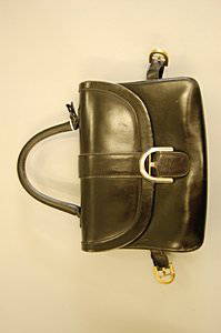 A Delvaux black leather handbag, late 1960s-early 1: A Delvaux black leather handbag, late 1960s-early 1970s, marked below the front flap Delvaux model depose, with straps at the sides and buckle closure, 26cm, 10in long