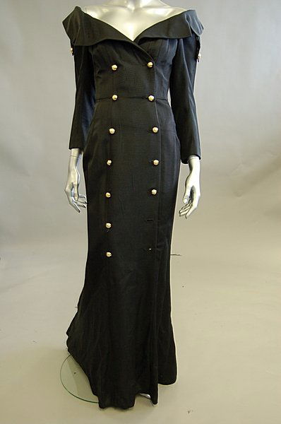 An Antony Price black silk faille `Parking Attenda: An Antony Price black silk faille `Parking Attendant' evening gown, 1990s, labelled, double breasted with gilt metal buttons, wide neckline with angular lapels, the fish-tail hem lined in yellow cotto
