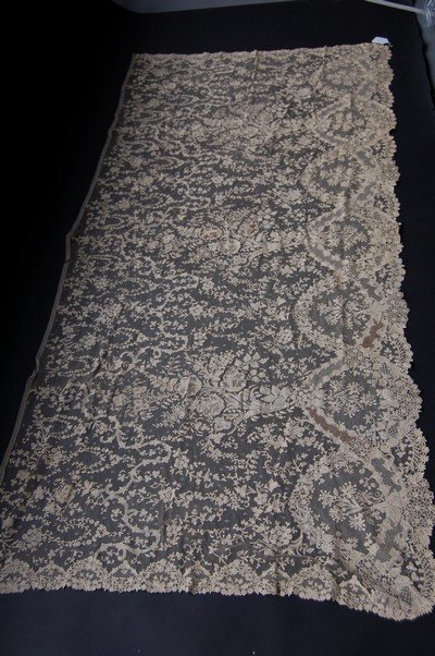 A good flounce or apron panel of Brussels bobbin: A good flounce or apron panel of Brussels bobbin application, circa 1860, with finished borders on three sides, worked with large sprays of tulips, forget-me-nots and other blooms with needlepoint fil