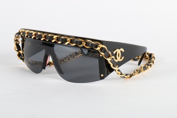 A pair of Chanel sunglasses, 1991, the upper frames: A pair of Chanel sunglasses, 1991, the upper frames applied with traditional leather threaded gilt linked chains; in fitted case; and a quilted leather Chanel spectacle case (3)Provenance: Hannelore S
