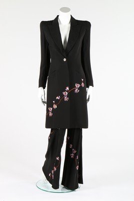 An Alexander McQueen for Givenchy embroidered black: An Alexander McQueen for Givenchy embroidered black crepe trouser suit, late 1990s, couture labelled and size 36, the coat with accentuated padded shoulders, embroidered to the front with mauve blosso