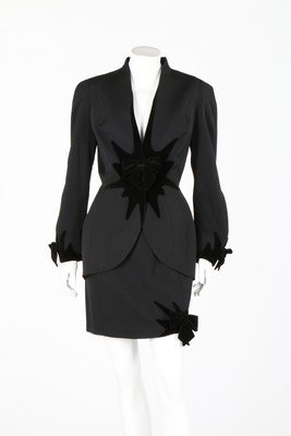 Two Thierry Mugler suits, early 1990s, blue labels size: Two Thierry Mugler suits, early 1990s, blue labels size 38, comprising wool suit with black velvet starburst to waist and black bows; the other of black wool with knitted sleeves, collar, skirt back a