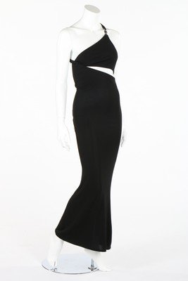 A Gianni Versace black silk jersey slashed-effect: A Gianni Versace black silk jersey slashed-effect evening gown, 1994, couture labelled and size 40, the bodice with asymmetric neckline, shoulder strap with rhinestone inset medusa buckle, bust approx