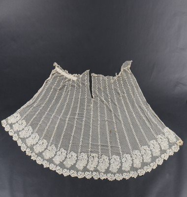 A Brussels needlepoint applique skirt panel circa: A Brussels needlepoint applique skirt panel circa 1820-30, the droschel ground with leaf sprig stripes and spots, the hem with deep band of curving peacock feather and blossom motifs, approx 110cm lon