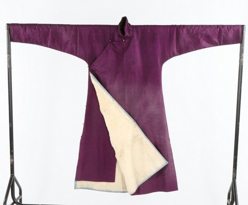 A purple damask woman's winter robe, Chinese circa: A purple damask woman's winter robe, Chinese circa 1910, woven with large peony roundels, entirely lined in white fur and edged in blue silk, gilt bauble fasteners, chest 117cm, 42in A percentage of t