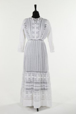 A day dress, circa 1914, of white cotton, the bodice: A day dress, circa 1914, of white cotton, the bodice and skirt with pin tuck, openwork and couched decoration and button fastening to the back