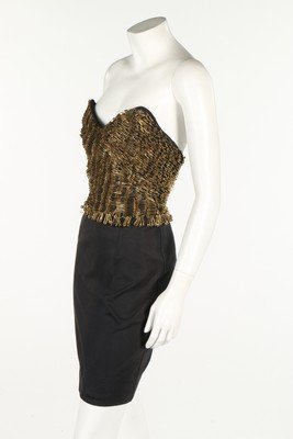 A Moschino black jersey cocktail dress with safety: A Moschino black jersey cocktail dress with safety pinned bodice, circa 1993. woven heart label, the black strapless bustier covered with rows of gilt pins, bust 81cm, 32in